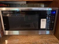 Front view of Sharp Carousel stainless steel microwave oven on a kitchen counter with digital display and control panel visible.