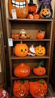 Wide view of wooden shelving unit with five shelves holding various Halloween pumpkin decorations