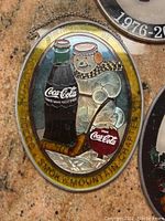 Close-up of oval Coca Cola sun catcher featuring a snowman with a bottle and hockey stick, marked 'Smoky Mountain Chapter 99'.