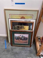 Five framed art prints stacked against a wall, mostly Civil War themed.