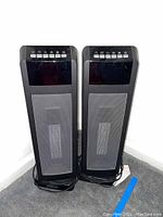 Two black Hunter HPQ15C-EA tower fans side by side, showing full front with mesh grille and control panel on top.