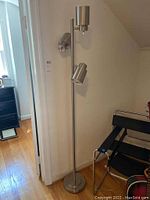 Full view of the floor lamp standing upright showing the three adjustable lamps on one pole with a round base.