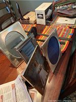 Multiple picture frames including rectangular and oval metal frames, wood frame with photo, silver chafing dish and box on wooden table