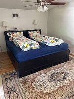 Full view of assembled king size Ikea Brimnes bed frame with mattress and bedding, showing four drawers on base.