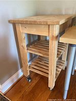 Full view of the Ikea Bekvam butcher block kitchen cart showing wood tabletop, legs, shelves, and wheels.