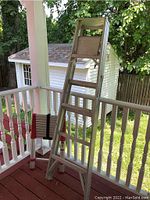 6-foot aluminum step ladder standing on a porch with red flooring and white railing
