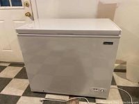 Front and side profile of white chest freezer on tiled floor