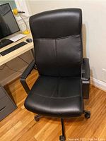 Front view of black office chair showing cushioned seat, backrest, and armrests.