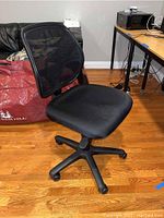 Office chair showing the side view with mesh back, cushioned fabric seat, and five-legged base with casters on hardwood floor.