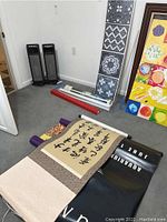 Photo showing rolled fabric art posters including Asian calligraphy piece, black aquarium-themed piece, and rolled art with colorful aquarium poster and tile patterns visible.