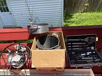 View of all items included: propane burner, deep fryer basket in pot, stock pot, and grill tool set.