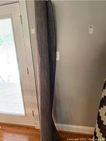 Rolled up IKEA gray rug showing texture and color under indoor lighting.