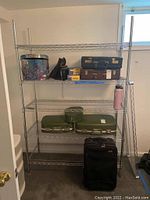 Full view of large metal wire storage shelf with 6 shelves. Various suitcases and containers placed on shelves (contents not included).