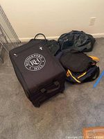 Photo showing all bags including Rutherford Hill rolling wine carrier and three duffel/briefcase bags on carpeted floor.