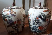 Pair of ceramic Asian ginger jars with lids, showing decorated bird and floral motifs, front and side view