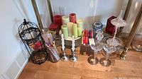 Wide shot showing all candle holders, pillar candles, tapered candles, and bird cage style candle holder grouped on the floor