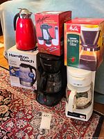 Full view of all items including coffee makers, vacuum container, red carafe, and kettle in boxes.