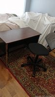 Desk and chair setup on patterned carpet, partially covered furniture in background