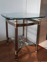 Full view of glass and metal end table showing rectangular glass top, metal legs, and quarter-circle glass lower shelf.