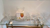 Photo of glassware set on a glass shelf showing serving trays, bowled and glasses