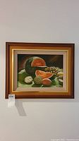 Frontal view of original signed oil painting showing detailed fruit still life in frame
