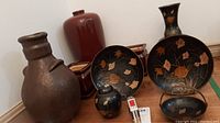 Various pottery and black glazed brass items with orange floral decoration, showing condition and size.