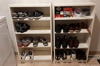 Two white wooden shelving units filled with shoes and boxes to show scale and shelving arrangement. Shelving units have scratches and wear visible.