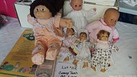 Overview of the five dolls including the Cabbage Patch Kids doll and four additional baby dolls showing their size, clothing, and condition.