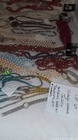 Wide view showing multiple vintage costume jewelry pieces on display including necklaces of bead and chain types, bracelets and earrings.