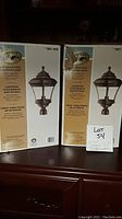Two boxes of Hampton Bay exterior post lantern lights, showing product branding and style on packaging.