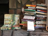 Box with assorted notecards and books arranged on a stone ledge in front of a fireplace