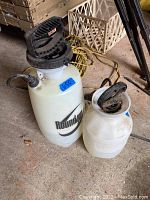 Photo shows two garden sprayers on concrete floor labeled Roundup.