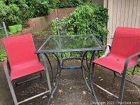 Full view of outdoor table and two matching chairs on patio ground