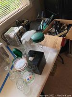 Shows toaster, glass pitchers with green lids, lidded glass jars, and kitchen utensil storage.