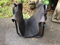 Front view of black metal and canvas wood holder showing carrier straps and overall construction.