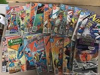 Overview of 25 vintage Superman Action Comics laid out showing colorful covers in plastic sleeves.