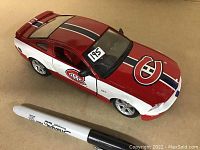 Top side view of the diecast model showing the hood and side Montreal Canadiens logos, Mustang body design, and scale comparison with a marker.