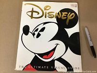 Front cover of vintage hardcover book featuring Mickey Mouse and Disney logo with gold and black print, showing the title 'The Ultimate Visual Guide'
