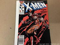 Front cover of The Uncanny X-Men #212 comic book featuring Wolverine in brown and tan costume fighting Sabretooth.