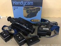 Photo showing Sony Handycam Video8 camcorder with original box, charger, and batteries on a beige surface.