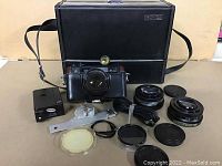 Full lot of vintage Yashica camera, lenses, flash, accessories, and carry case displayed
