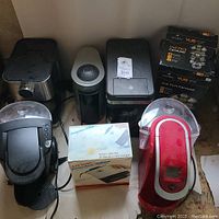 Overview of all coffee machines and accessories showing Keurig coffee makers, espresso machine, drip coffeemaker, coffee grinder, and boxed items