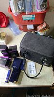 Overall view of black Coach cosmetic case, pink polka-dot lining interior, and assorted boxed cosmetics on table