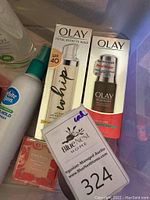 Photo shows Olay Total Effects Whip SPF 40 and Olay Regenerist Serum sealed in original boxes alongside a Covergirl blush with auction tag visible.