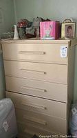 Front view of wooden dresser with items on top including lamps, lamp shades, candles, and a framed photo.