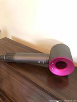 Hair dryer side view showing fuchsia ring around air outlet and controls