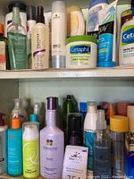 Shelf with various hair and beauty bottles including sprays, shampoos, and moisturizers from brands like Pantene, Pureology, Cetaphil, Olay, and more