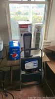 Overall lot with all four items: Lasko heater box, Aloha Breeze heater, Pepsi mini fridge, Cosco step stool