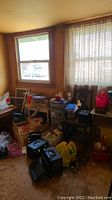 Wide view of attic room showing assorted boxes, cosmetic cases, storage bins, and some packed items on floor and against wall beneath window.