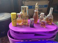 Cosmetic bottles including Jean Nate Color Stick, perfumes on purple organizer box